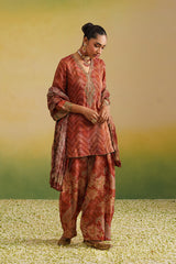 Woman wearing rust paisley and chevron printed farshi salwar set with embroidered neckline and dupatta